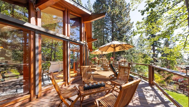 Una terraza de madera con mobiliario exterior y un cerramiento de vidrio.