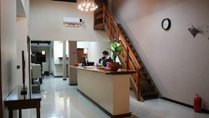 A spacious hotel lobby with a central reception desk, a staircase, and a clock on the wall. - Posada Del Jacarandá (Puerto Iguazú)