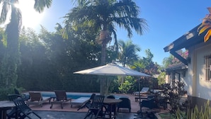 A patio with outdoor seating, a pool, and palm trees. - Posada Del Jacarandá (Puerto Iguazú)