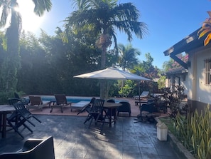 Une terrasse avec des sièges extérieurs, une piscine et des palmiers.