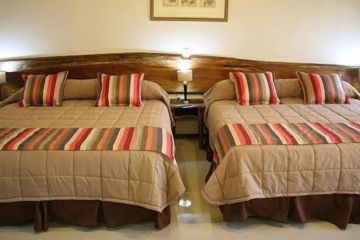 A room with two beds, each with striped bedding and wooden headboards.