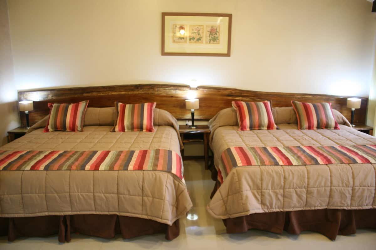 A double bed with a striped bedspread and two pillows, flanked by bedside tables with lamps.