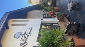 A building with a sign that reads 'Hotel de la Posada.' There is a large potted plant in the foreground. - Posada Del Jacarandá (Puerto Iguazú)