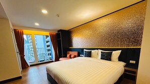 Una habitación de hotel moderna con una cama grande, un balcón con vistas y un detalle decorativo en la pared.