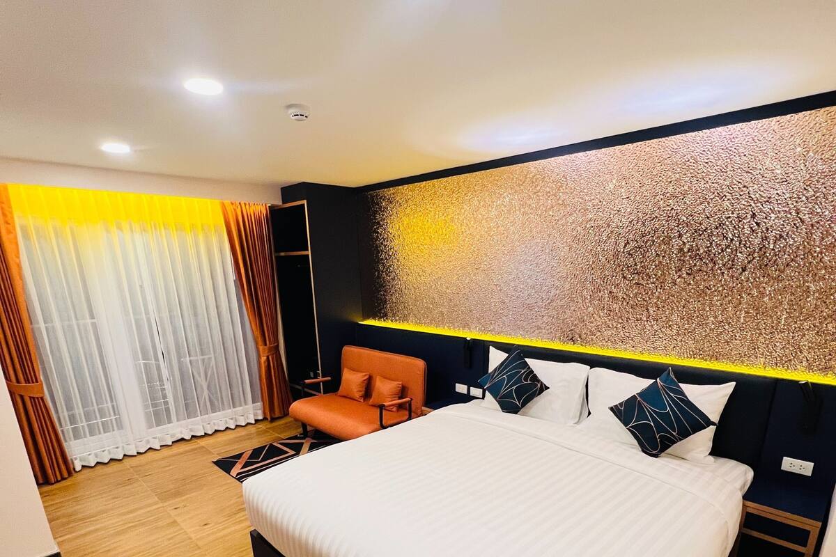 A modern bedroom with a large bed, a sofa, and a decorative wall.