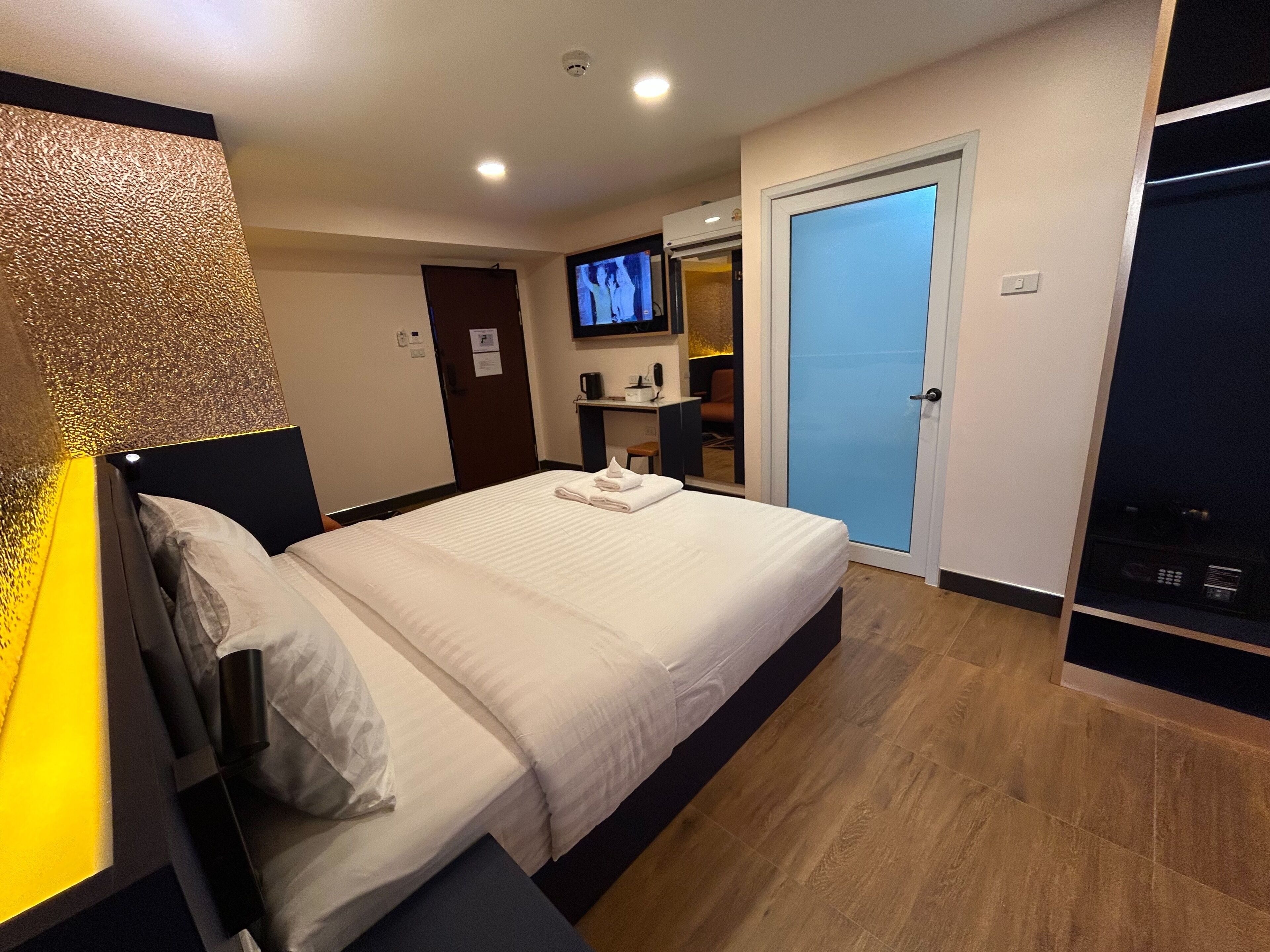 Habitación de hotel con una cama grande, un televisor montado en la pared, un escritorio con silla y un armario.
