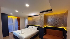 Una habitación de hotel moderna con una cama grande, un área de descanso y una pared decorativa.
