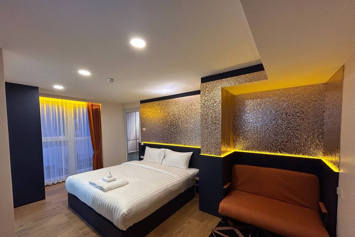 A modern hotel room with a large bed, a seating area, and a decorative wall.