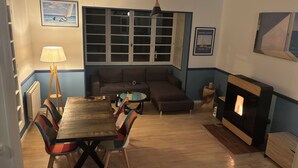 Una sala de estar acogedora con una mesa de comedor de madera, sillas coloridas, un sofá y una chimenea.