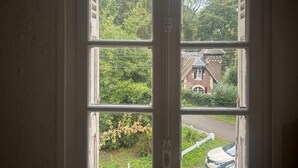 Vista a través de un doble vano con múltiples cristales, mostrando una zona residencial con vegetación y una casa de ladrillo.