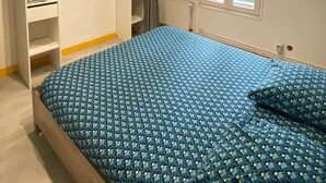 Ein Schlafzimmer mit Bett, Kleiderschrank, Fenster und Heizkörper.