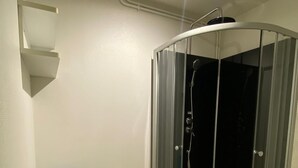 Ein Badezimmer mit einer Duschkabine, einem blauen Stuhl und einer kleinen Fußmatte.