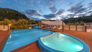 Una piscina con idromassaggio, lettini prendisole e un pontile in legno.