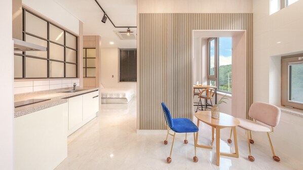 A modern kitchen with a central island, a dining area with a table and chairs, and a view of the outdoors through a window.