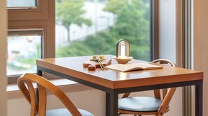 Une table en bois sur laquelle se trouvent un livre, une petite plante et un récipient en verre doté d’un couvercle en métal.