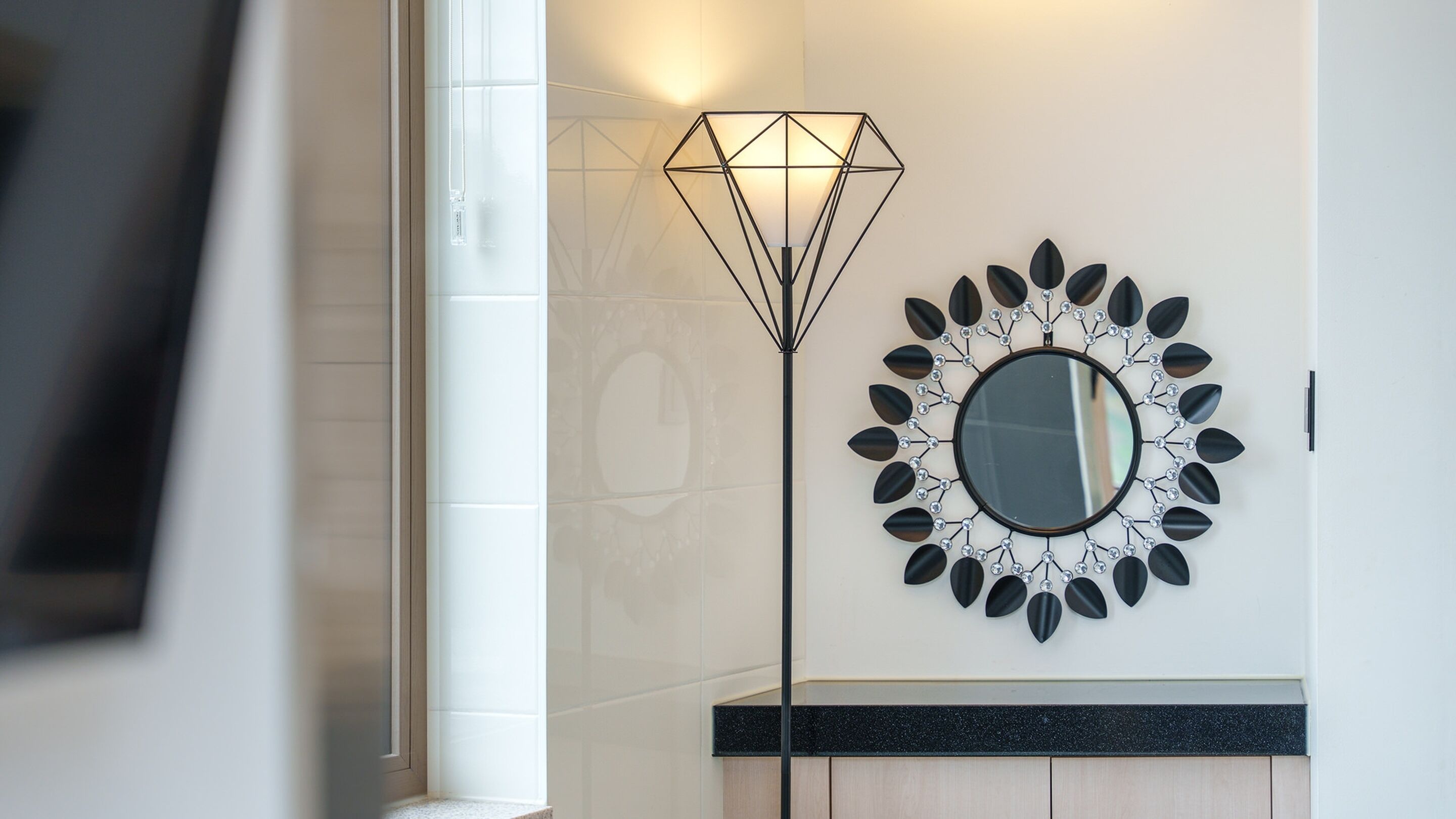 A modern interior with a geometric floor lamp and a decorative mirror on the wall.
