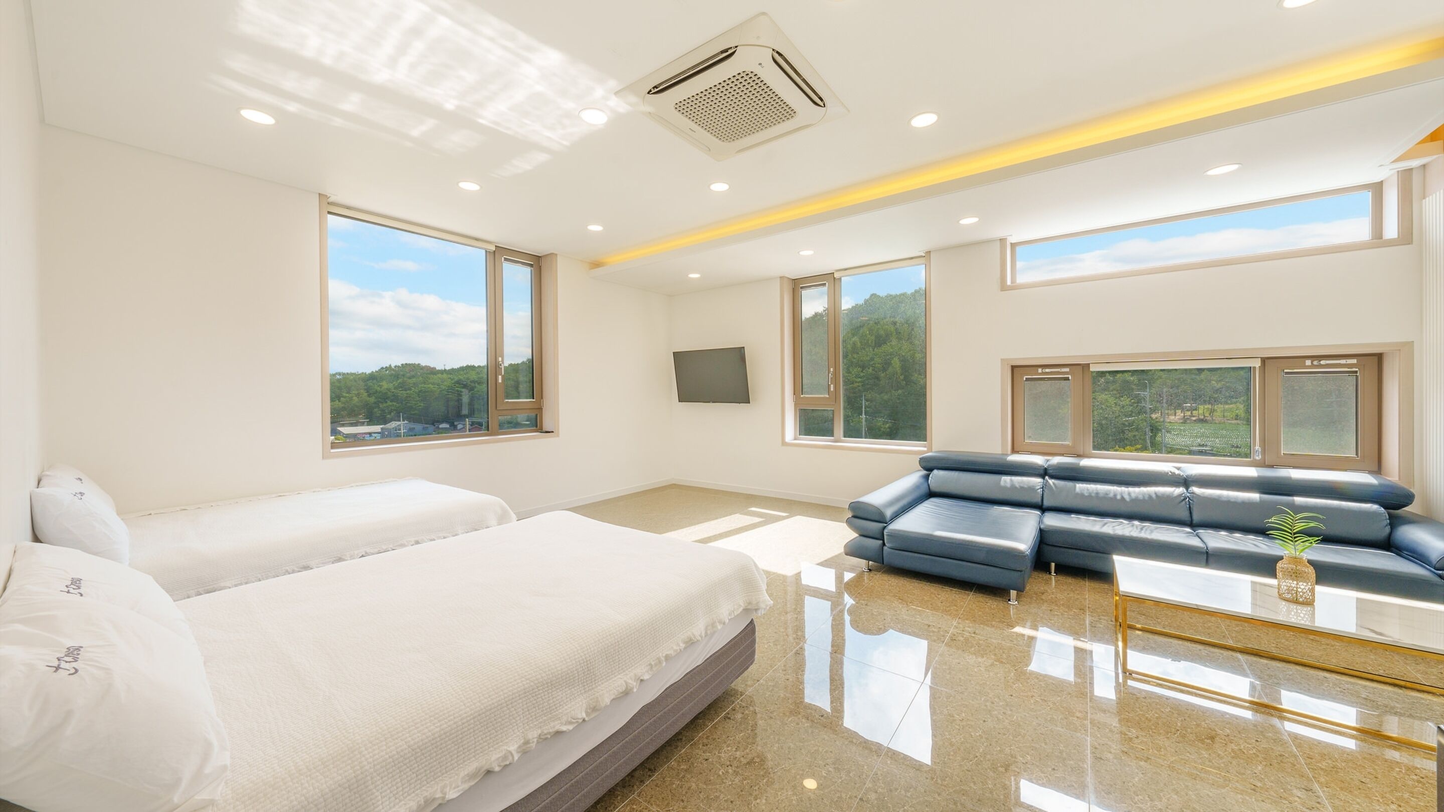 Una habitación de hotel moderna con una cama grande, un sofá azul y un televisor.