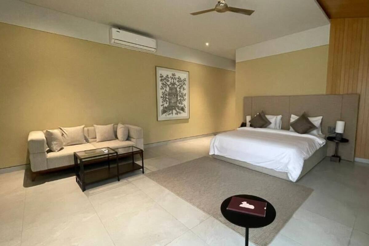 A modern bedroom with a bed, a sofa, a coffee table, and a painting on the wall.