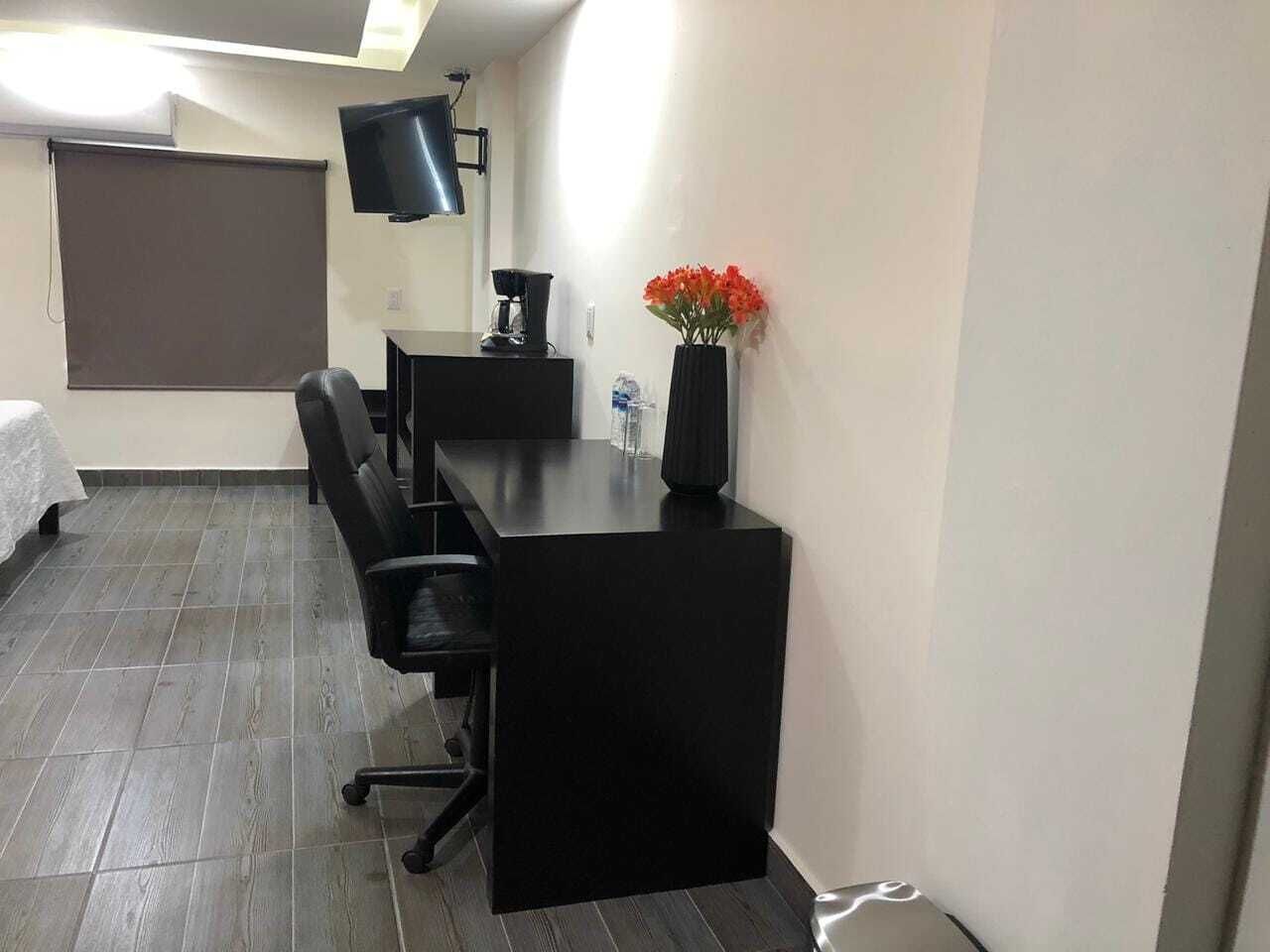 A conference room with a black table, chairs, a projector, and a vase with flowers.