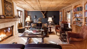 A cozy living room with a fireplace, bookshelves, and a large painting on the wall. - Beautiful Alpine Luxury Flat in Rougemont (Rougemont)