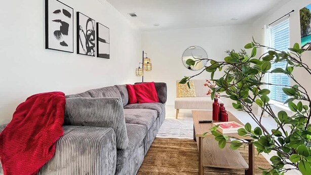 A modern living room with a grey sofa, red throw, and a wooden coffee table.