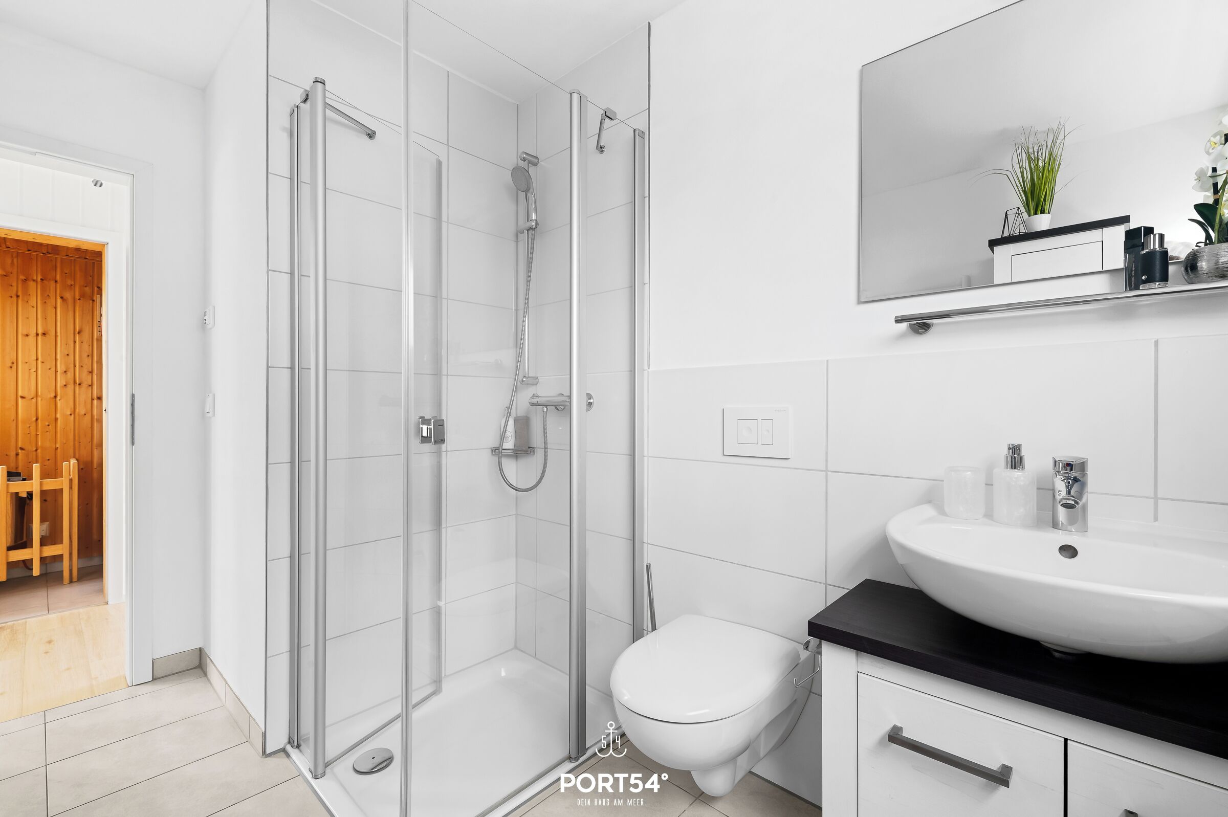 A modern bathroom with a glass-enclosed shower, a white toilet, and a large mirror above the sink.