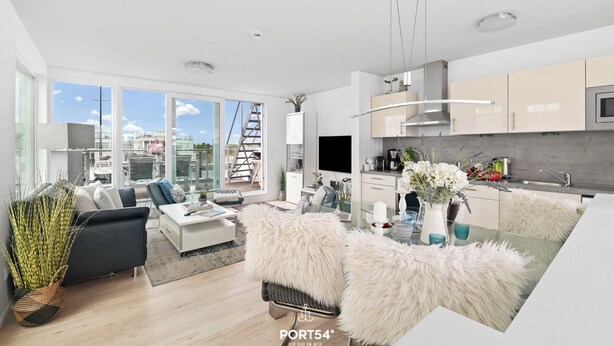 A modern living room with a sofa, coffee table, and a dining area with a glass table. - Biscaya - Sauna, Shower, 360° Panoramic Rooftop Terrace, Floating House (Olpenitz)