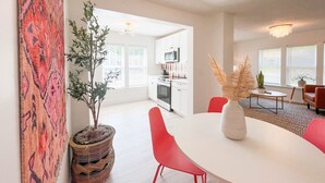 Un espace repas moderne avec une table blanche, des chaises rouges et une plante en pot.