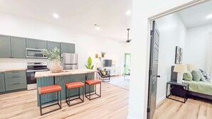 Eine moderne Küche mit einer zentralen Kochinsel, Barhocker und einem Essbereich mit Sofa und Tisch.