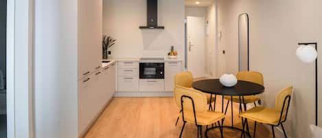 A modern kitchen with white cabinets, a black stove, and a round dining table with yellow chairs.