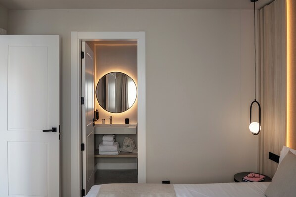 Habitación de hotel con cama, mesita de noche, armario y una lámpara colgante.