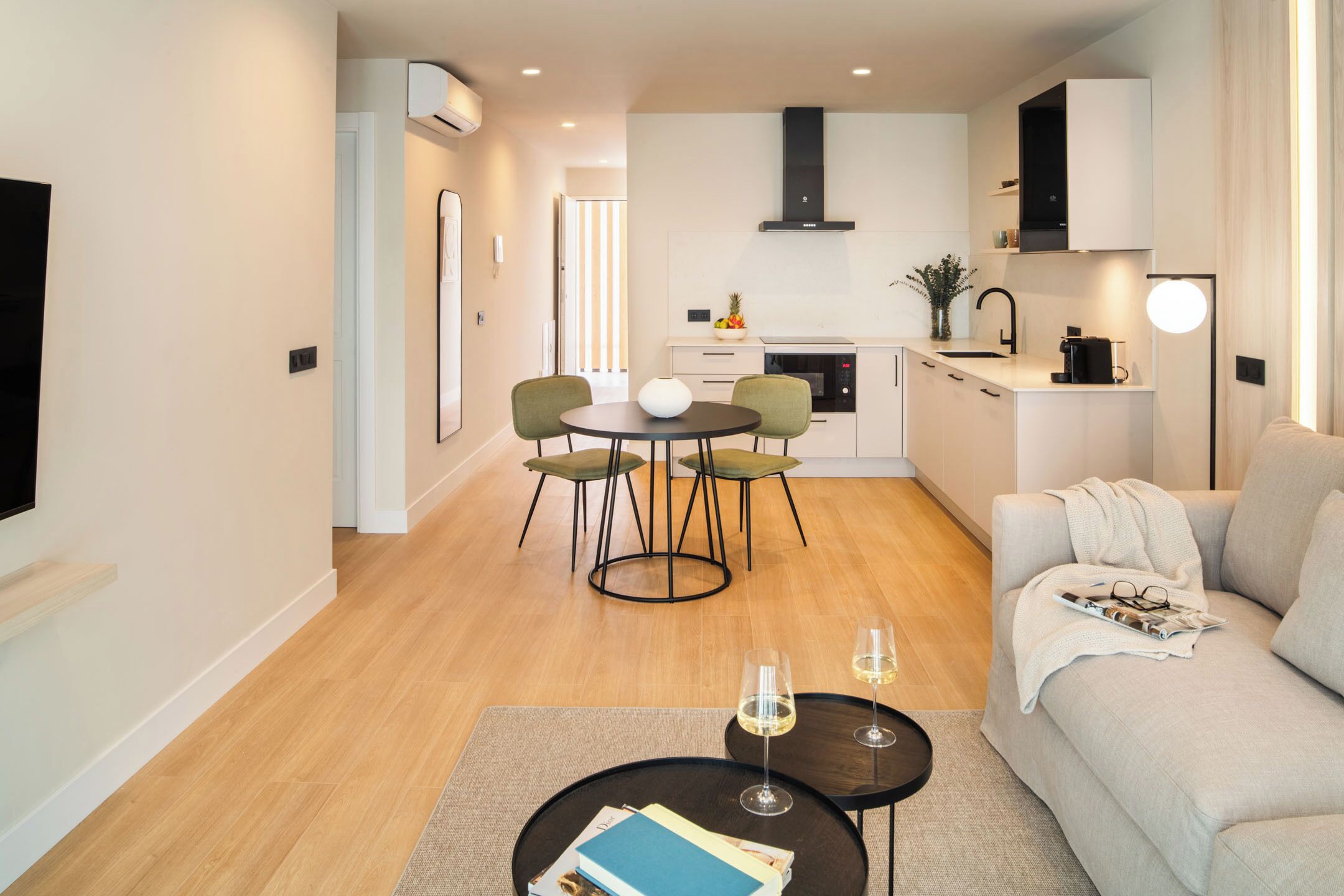 A modern living room with a sofa, a coffee table, and a dining area with chairs and a table.