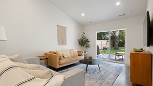 Una sala de estar moderna con un sofá, una mesa de centro y un televisor sobre un mueble de madera.