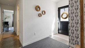 Un pasillo con una puerta negra, alfombra gris y tres adornos de madera en la pared.