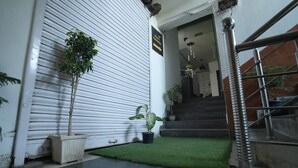 A hotel entrance with a closed shutter door, a staircase, and potted plants. - Hotel Kohinoor (New Delhi)