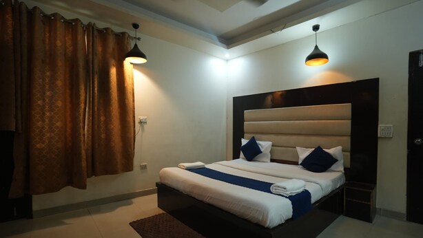 A modern hotel room with a large bed, two bedside lamps, and a dark headboard. - Hotel Kohinoor (New Delhi)