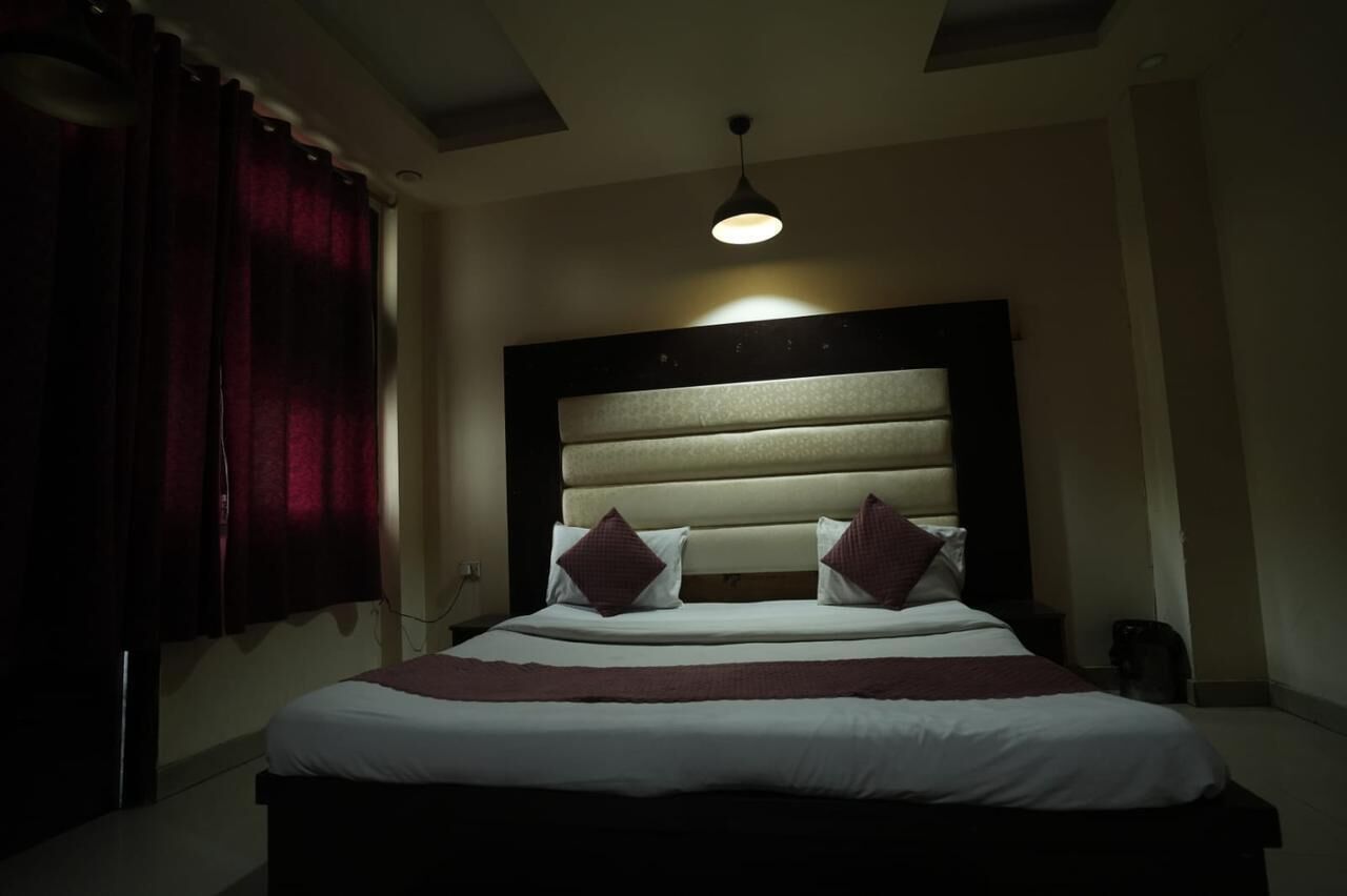 Une chambre d’hôtel avec un grand lit, une tête de lit et un luminaire au plafond.