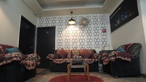 A living room with a sofa set, a coffee table, and a patterned wall. - Hotel Kohinoor (New Delhi)