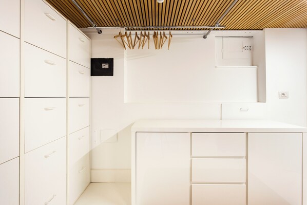 A modern, white interior with a wooden ceiling, a built-in kitchen counter, and a wall-mounted light fixture. - Charm and Style in the Heart of Catania (Catania)