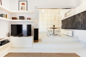 A modern living room with a flat-screen TV, a coffee table, and a dining area with chairs. - Charm and Style in the Heart of Catania (Catania)