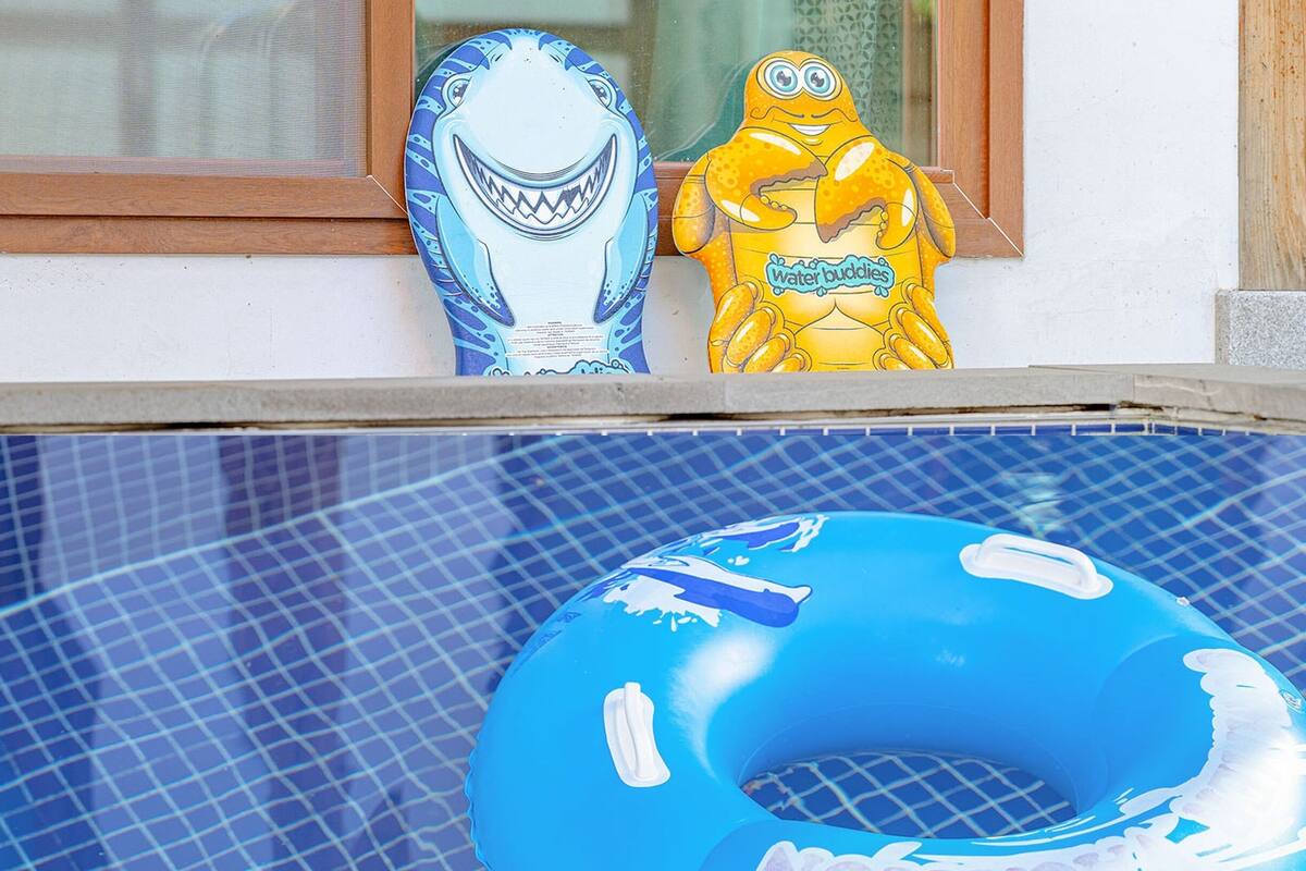 A pool with a blue inflatable ring and two decorative shark figures on the edge.