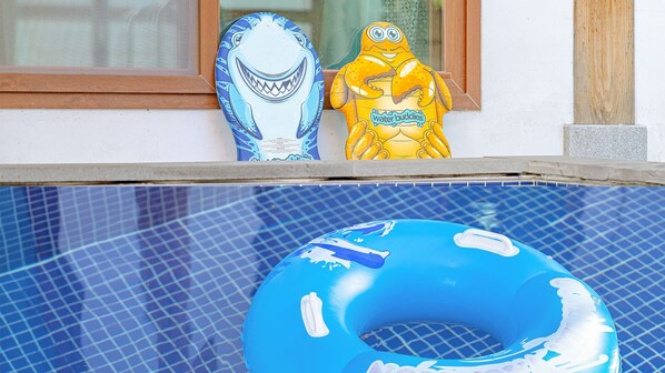 A pool with a blue inflatable ring and two decorative shark figures on the edge. - Gyeongju Adamwon Hanok Dokchae Pension (Gyeongju)
