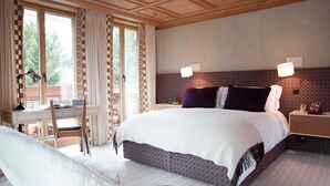 Een slaapkamer met een groot bed, een bureau en een stoel. Er zijn twee nachtkastjes met lampen.