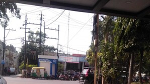 A paved area with a parked scooter and a bicycle, a milk parlor, and a building with signage in a foreign language. - Hotel Siddhartha (Ujjain)
