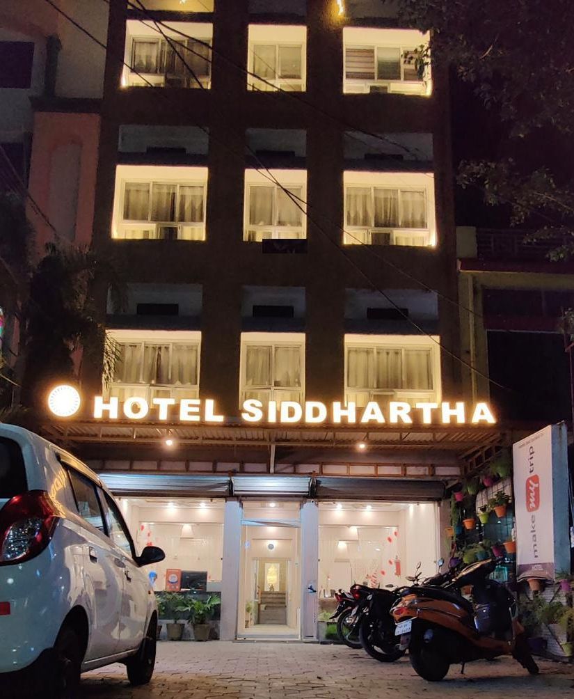 Ein Hotel mit einem Schild, auf dem 'HOTEL SIDDHARTHA' steht, bei Nacht.
