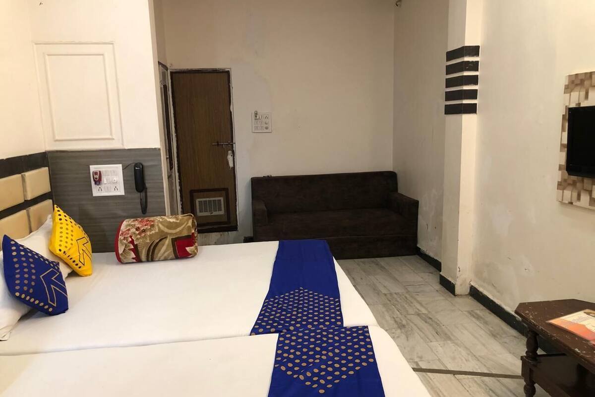 Ein Hotelzimmer mit zwei Betten, einem Sofa, einem Fernseher und einem kleinen Tisch.