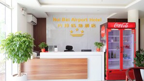A reception desk with a Coca-Cola refrigerator, potted plants, and a sign for Noi Bai Airport Hotel. - Noi Bai Airport Hotel  (Hanoi)
