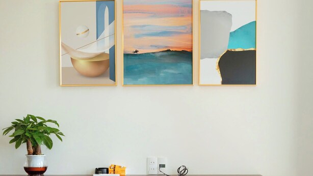A hotel room with a bed, a desk with a plant, and three framed artworks on the wall. - Noi Bai Airport Hotel  (Hanoi)