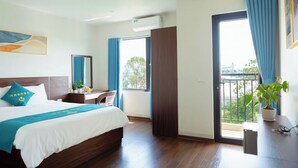 A hotel room with a bed, a desk, a potted plant, and a balcony with a view. - Noi Bai Airport Hotel  (Hanoi)
