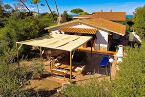 A villa with a patio, outdoor furniture, and a view of the sea. - Villino Saline (Orbetello)